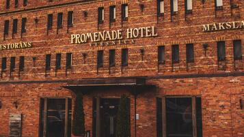 Un edificio in mattoni con il cartello "Promenade Hotel" e "Maksla".