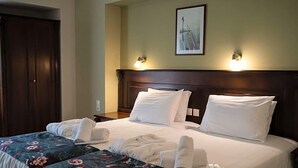 Una camera d'albergo con un letto grande, due comodini, una testiera e un quadro appeso alla parete.