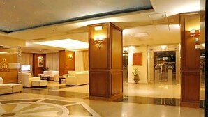 Una hall d'albergo con reception, area salotto e un ampio motivo decorativo sul pavimento.