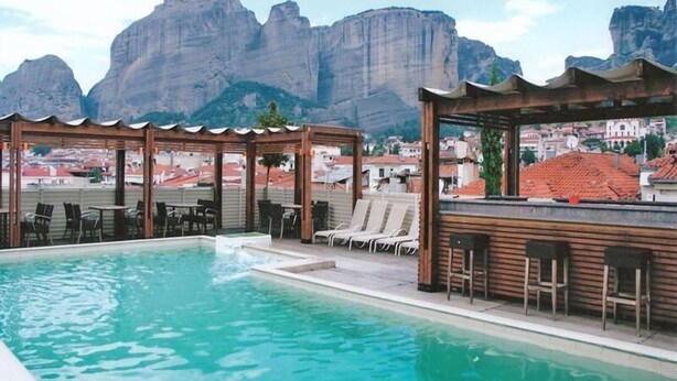 Una piscina sul tetto con lettini e un pergolato in legno, con vista su un paesaggio montuoso.