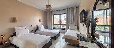 A hotel room with two beds, a large window, a TV, and a mirror.