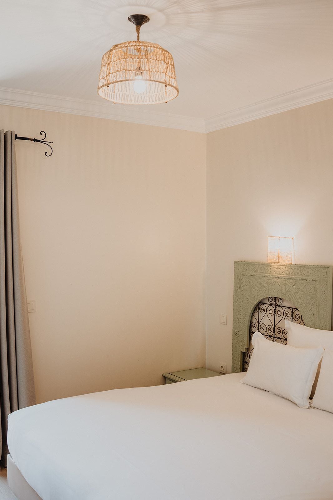 Une chambre à coucher comprenant un lit, une table de chevet, une lampe fixée au mur et un luminaire au plafond.