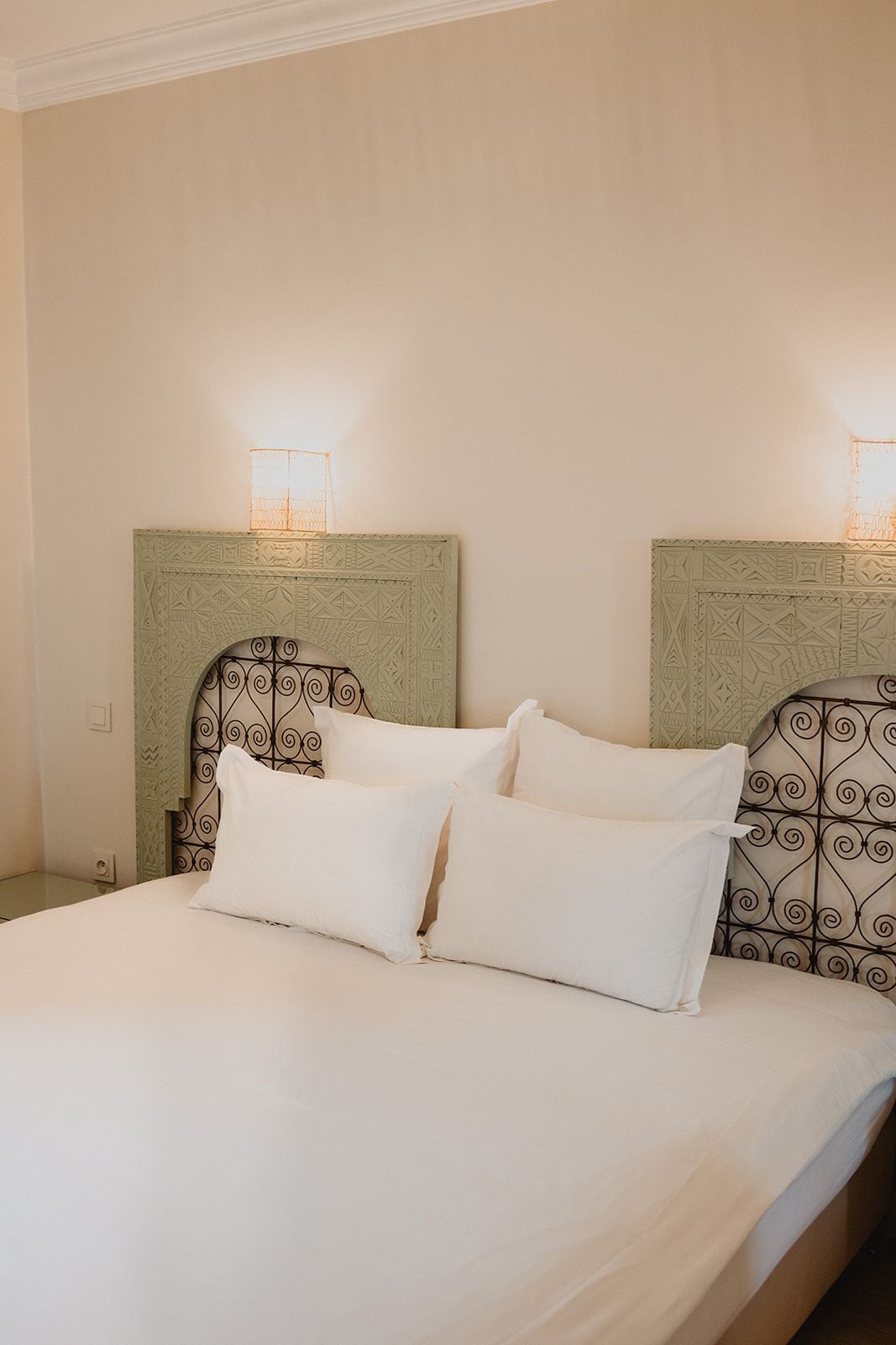 A bed with white bedding and two headboards with decorative patterns.