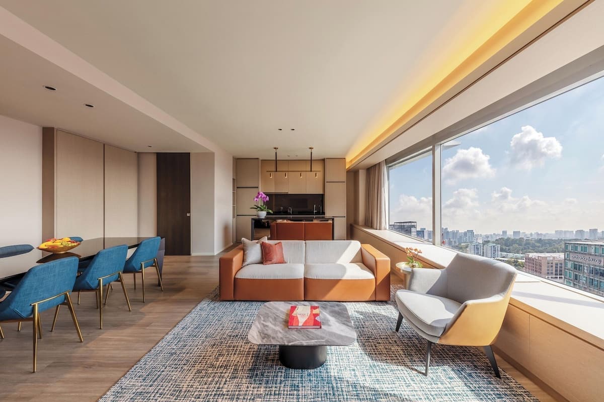 A modern living room with a sofa, chairs, a coffee table, and a large window with a city view.