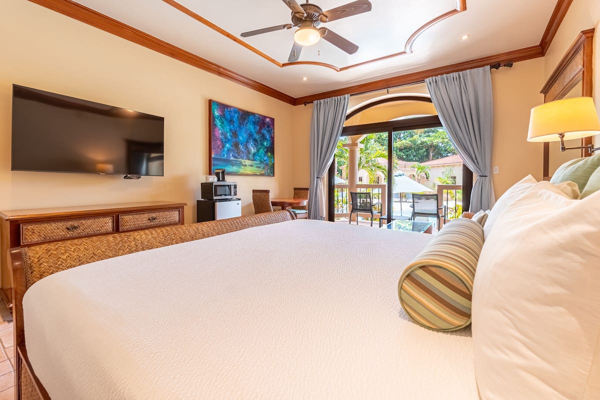 Estudio estándar, 1 cama de matrimonio grande, vistas a la piscina | 1 dormitorio, caja fuerte, tabla de planchar con plancha y cuna de viaje