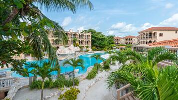 A resort with a pool, palm trees, and Mediterranean-style buildings.