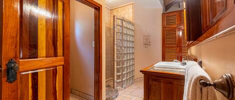 A wooden hallway with a door, a tiled floor, and a stone wall with a glass door.