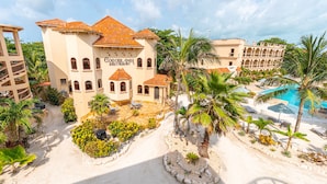 Un complexe hôtelier doté d’une piscine, de palmiers et d’un bâtiment portant l’inscription « Restaurant Cogoblanga ».