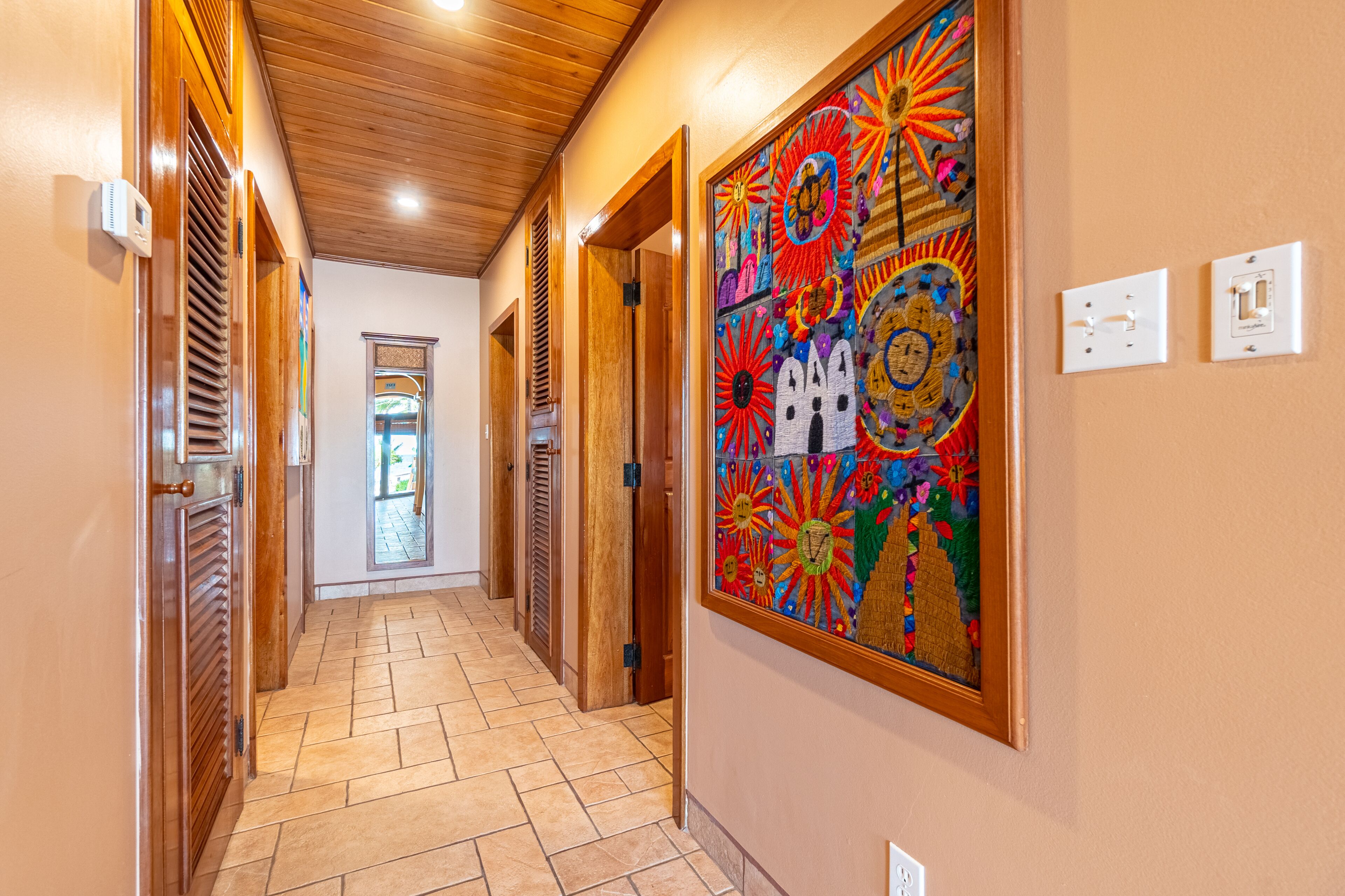 A hallway with wooden doors, a tiled floor, and a colorful mural on the wall.