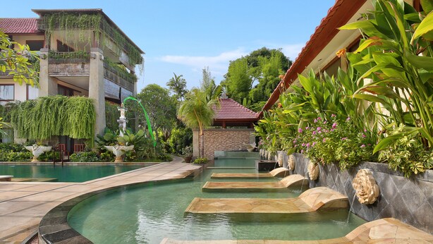 A pool area with clear water, stone steps, and surrounding greenery. - The Grand Bali Nusa Dua (Nusa Dua)