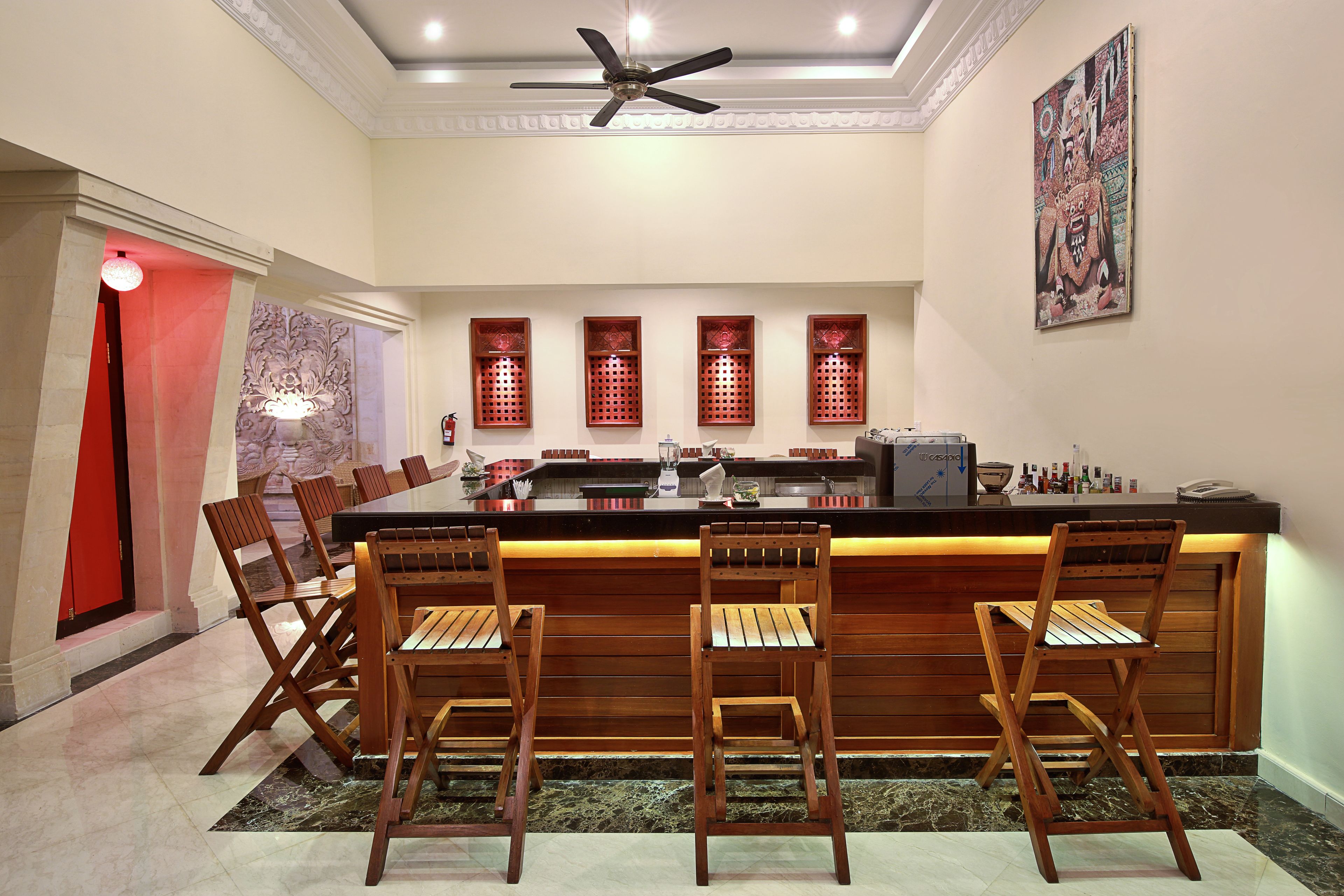 Una cocina moderna con barra, sillas de madera y ventanales decorativos.