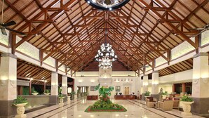 A spacious lobby with a high ceiling, a central chandelier, and a reception desk. - The Grand Bali Nusa Dua (Nusa Dua)