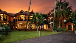 A resort with multiple buildings, a well-maintained lawn, and palm trees. - Ramada Resort by Wyndham Kochi (Kanayannur)