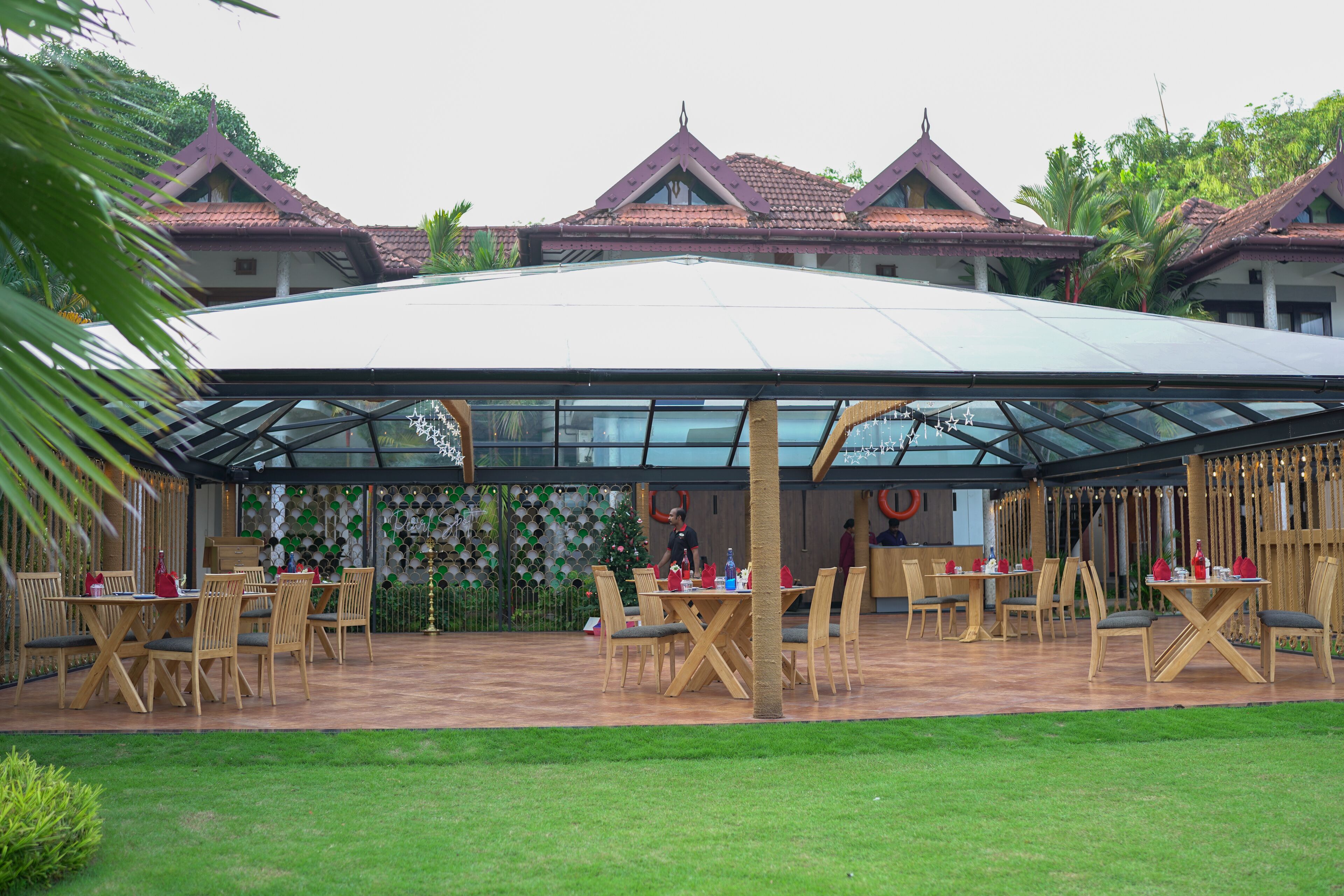 A covered outdoor dining area with tables and chairs, surrounded by buildings with traditional architecture.