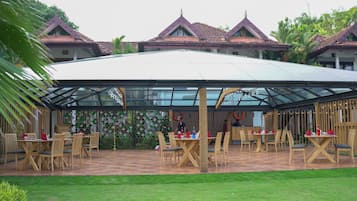 A covered outdoor dining area with tables and chairs, surrounded by buildings with traditional architecture.