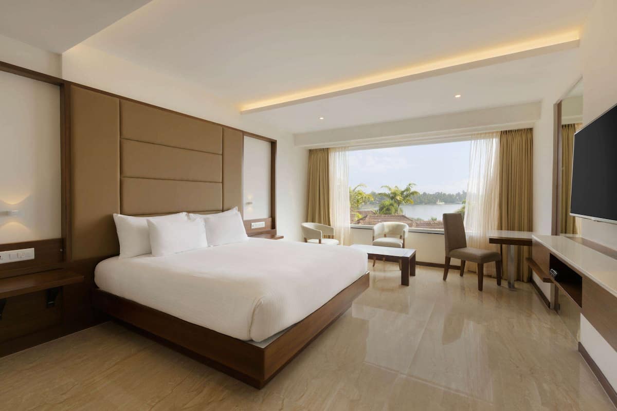 Quarto de hotel moderno com uma cama grande, uma escrivaninha, uma cadeira e uma televisão.
