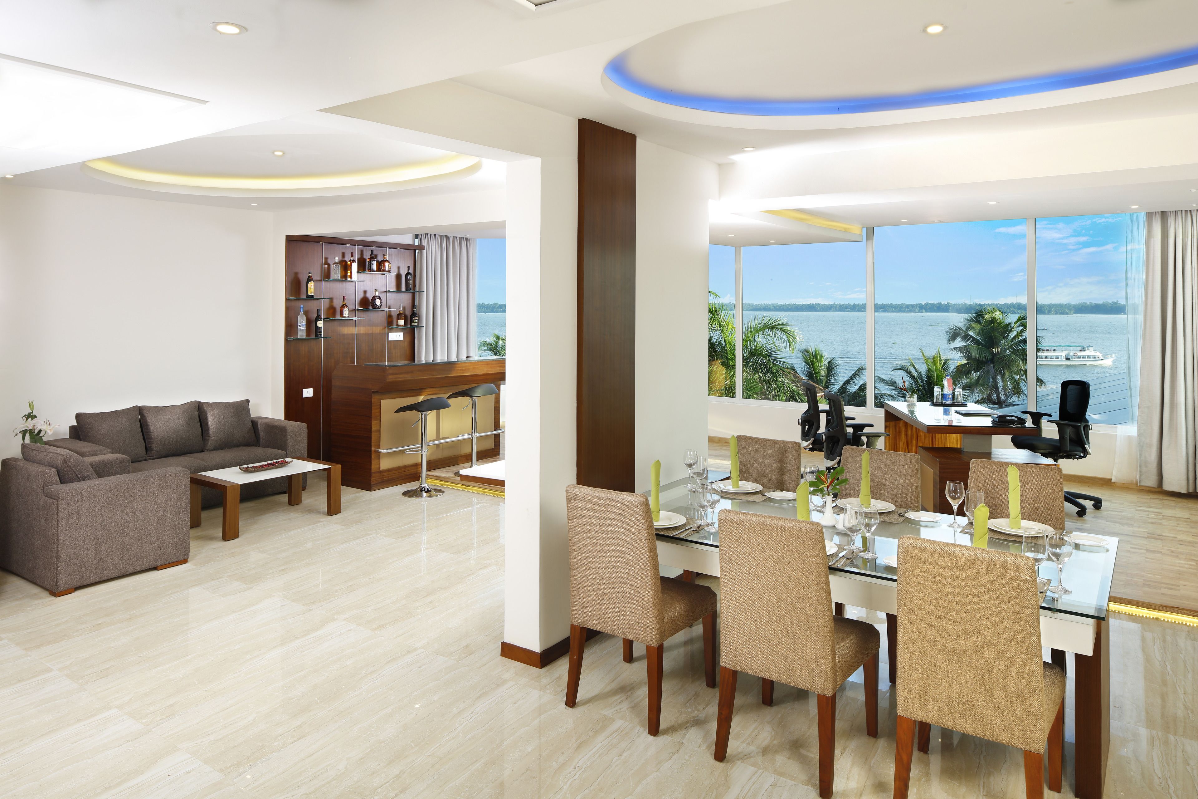 A modern hotel room with a dining area, a sofa, and a view of the sea.