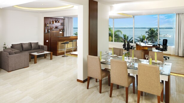 A modern hotel room with a dining area, a sofa, and a view of the sea. - Ramada Resort by Wyndham Kochi (Kanayannur)