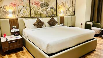 A spacious hotel room with a large bed, a nightstand, a desk, and a chair.