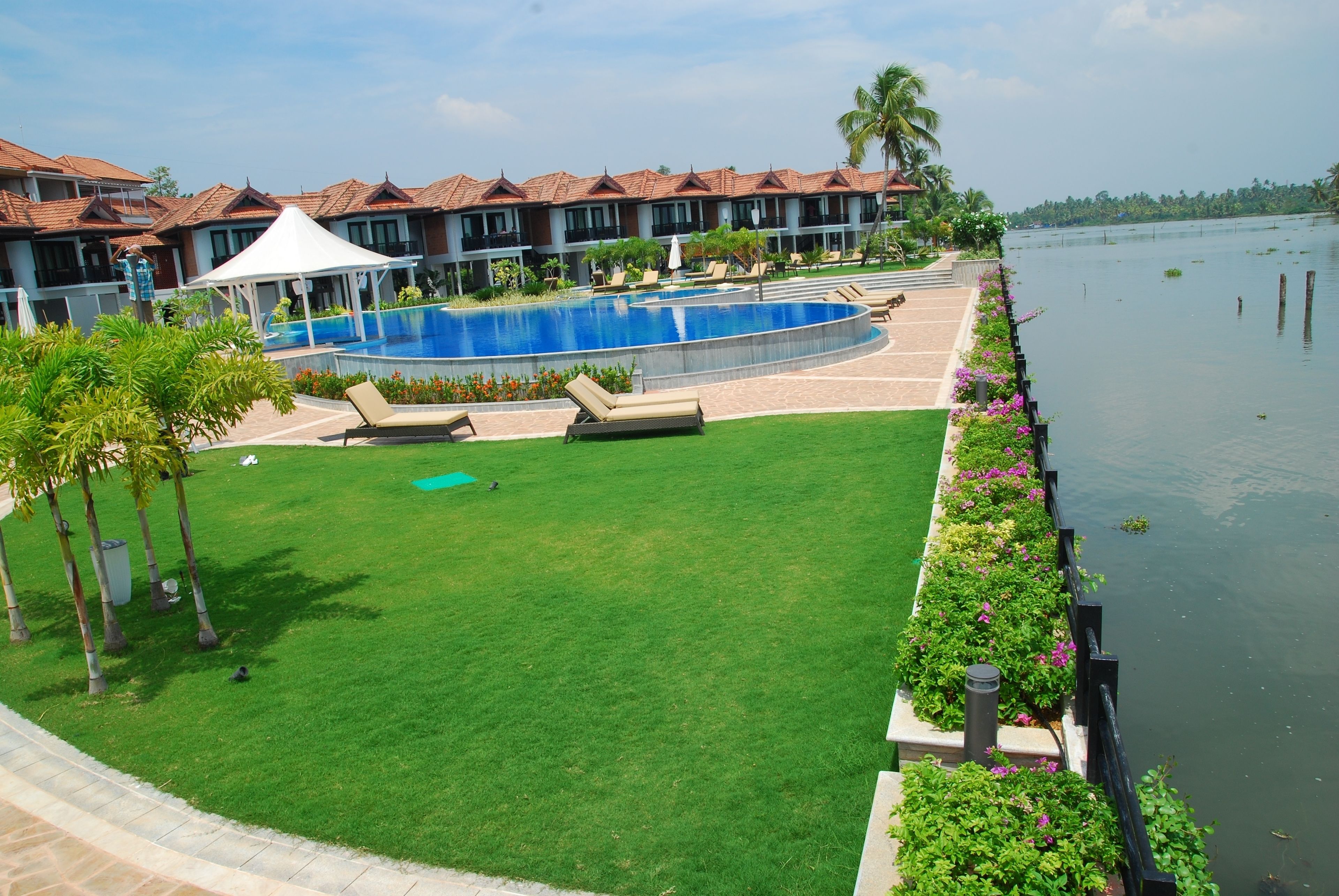 Ein Hotel mit Schwimmbad, Rasenfläche und Blick auf das Wasser.
