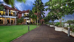 A waterfront property with a wooden walkway, lush greenery, and a two-story building with balconies. - Ramada Resort by Wyndham Kochi (Kanayannur)