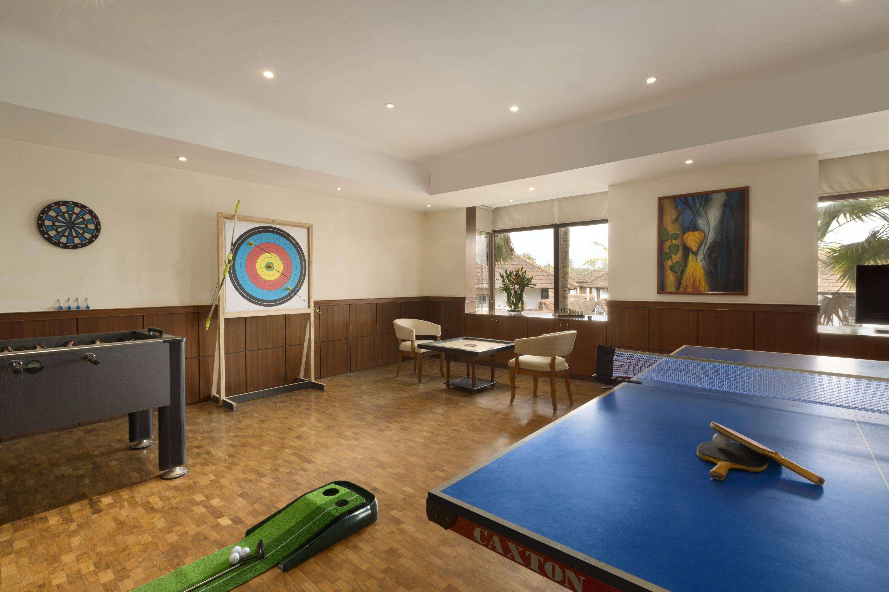 Een kamer met een tafelvoetbaltafel, dartbord en pingpongtafel.