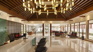 A spacious lobby with a reception desk, seating area, and large windows offering views. - Ramada Resort by Wyndham Kochi (Kanayannur)