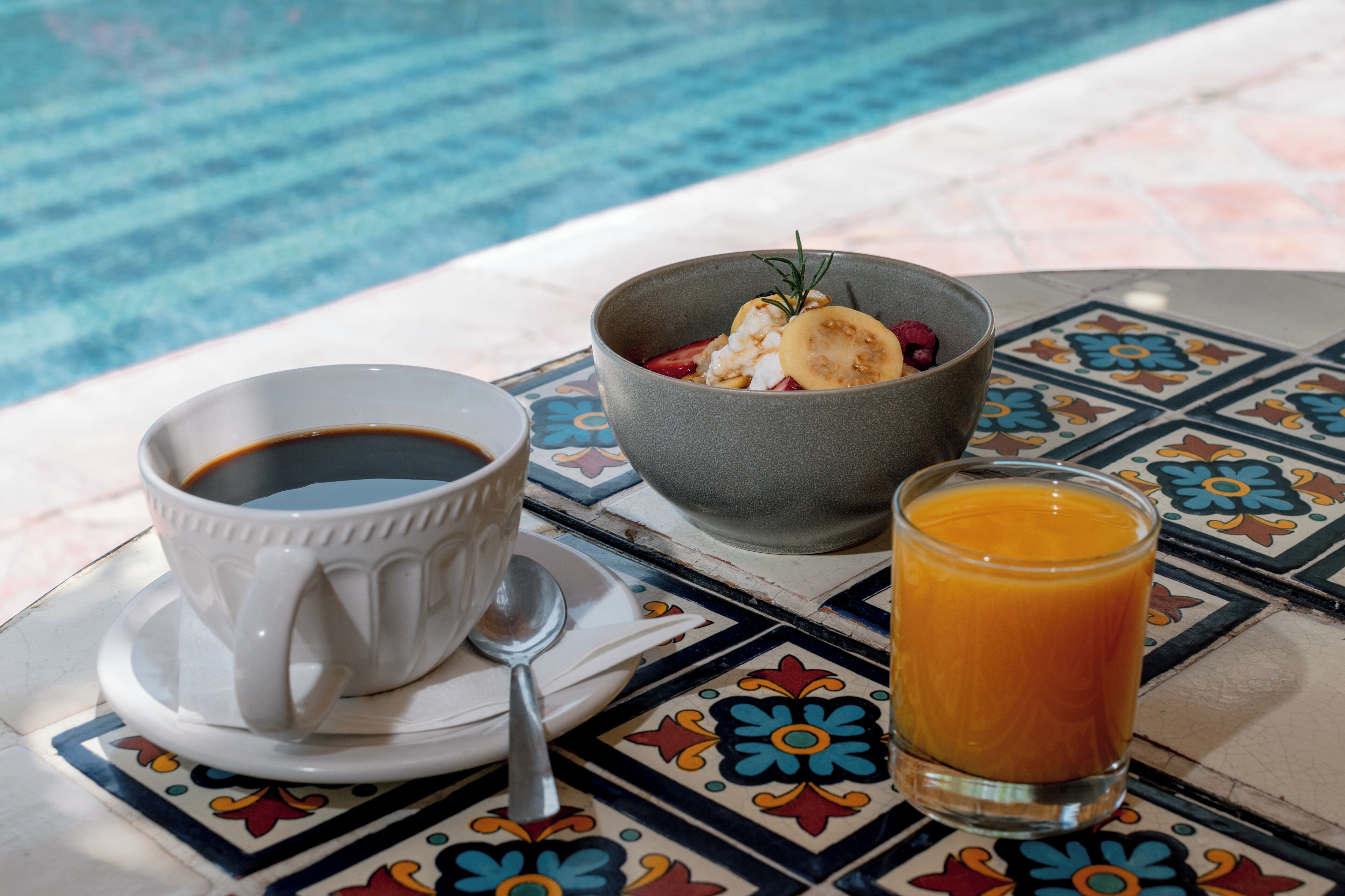 A table with a cup of coffee, a bowl of food, and a glass of orange juice.