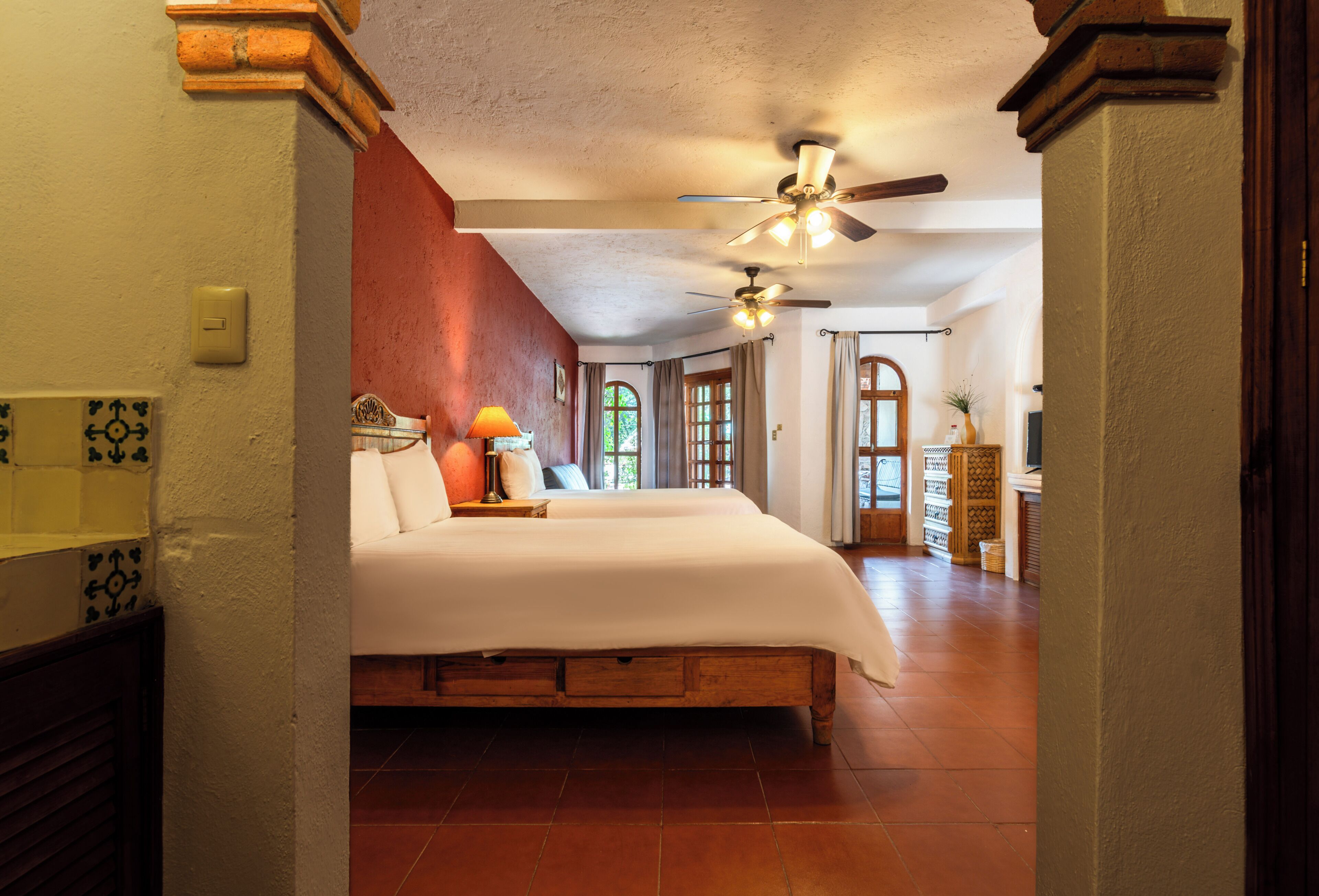A spacious bedroom with a large bed, a ceiling fan, and a view of the adjacent bathroom.