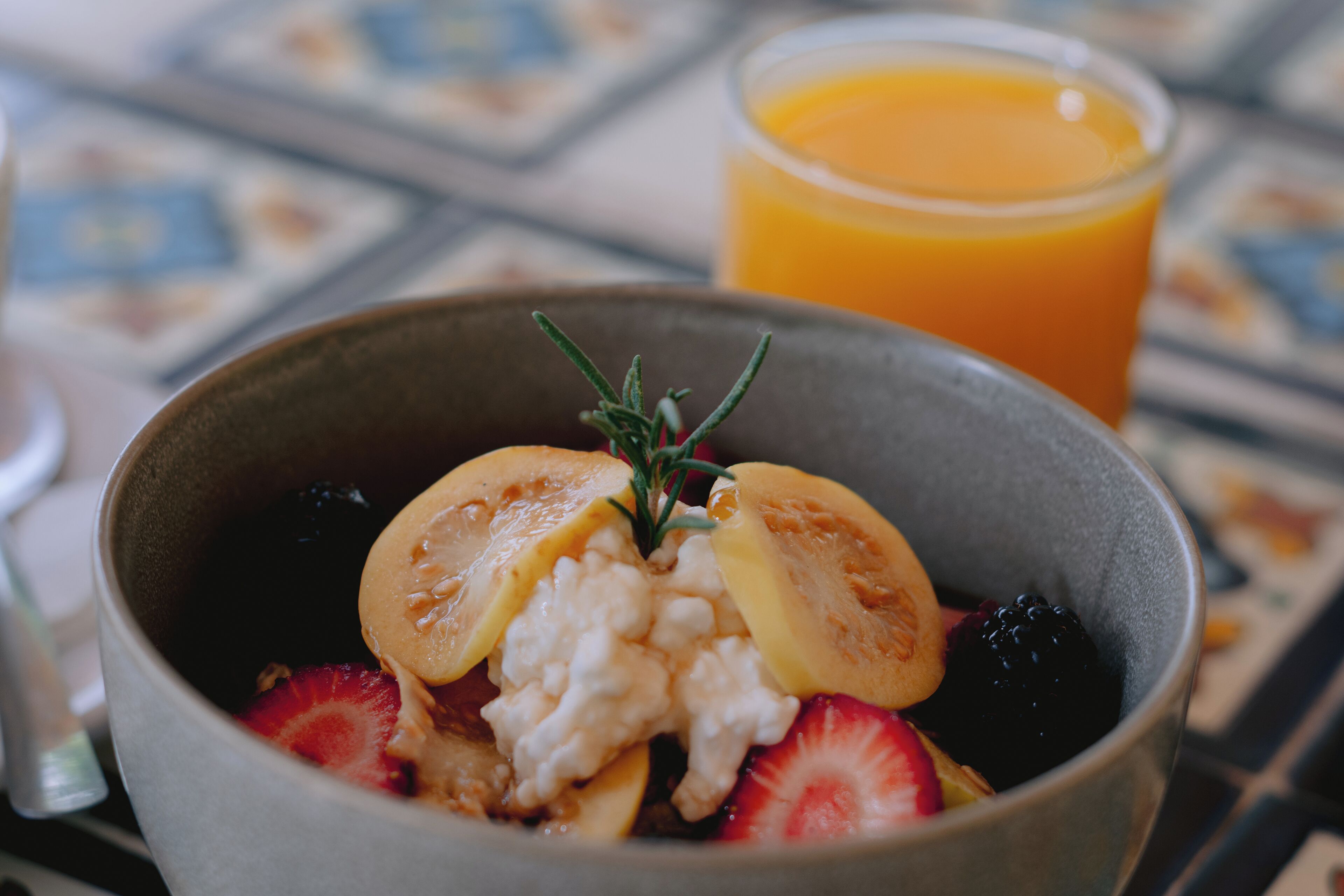 Un tazón de desayuno con frutas y un vaso de jugo de naranja.