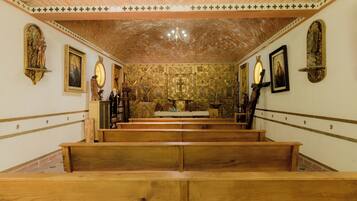 Interior de iglesia con bancales de madera, pinturas religiosas y techo de ladrillo.