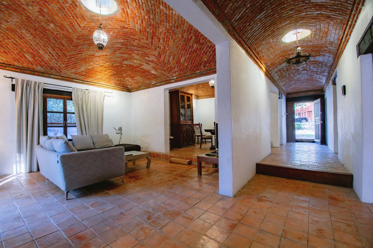 A spacious living area with a brick ceiling, a sofa, a coffee table, and a view through an open doorway.