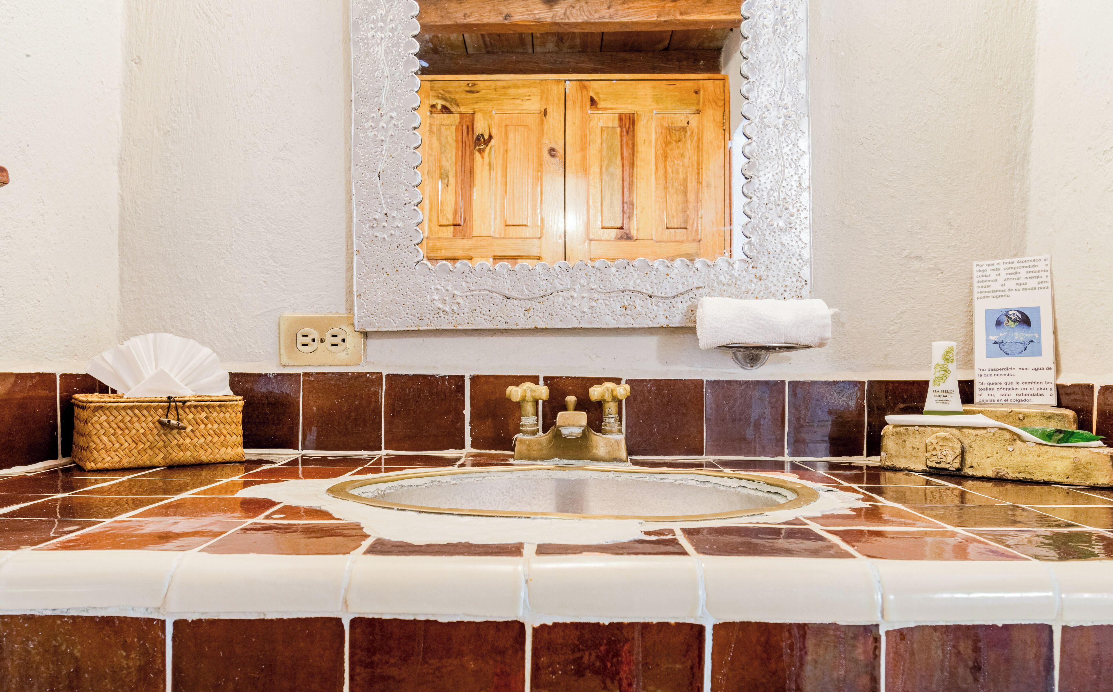 Un baño con bañera, una puerta de madera, un perchero, una cesta y un cartel.