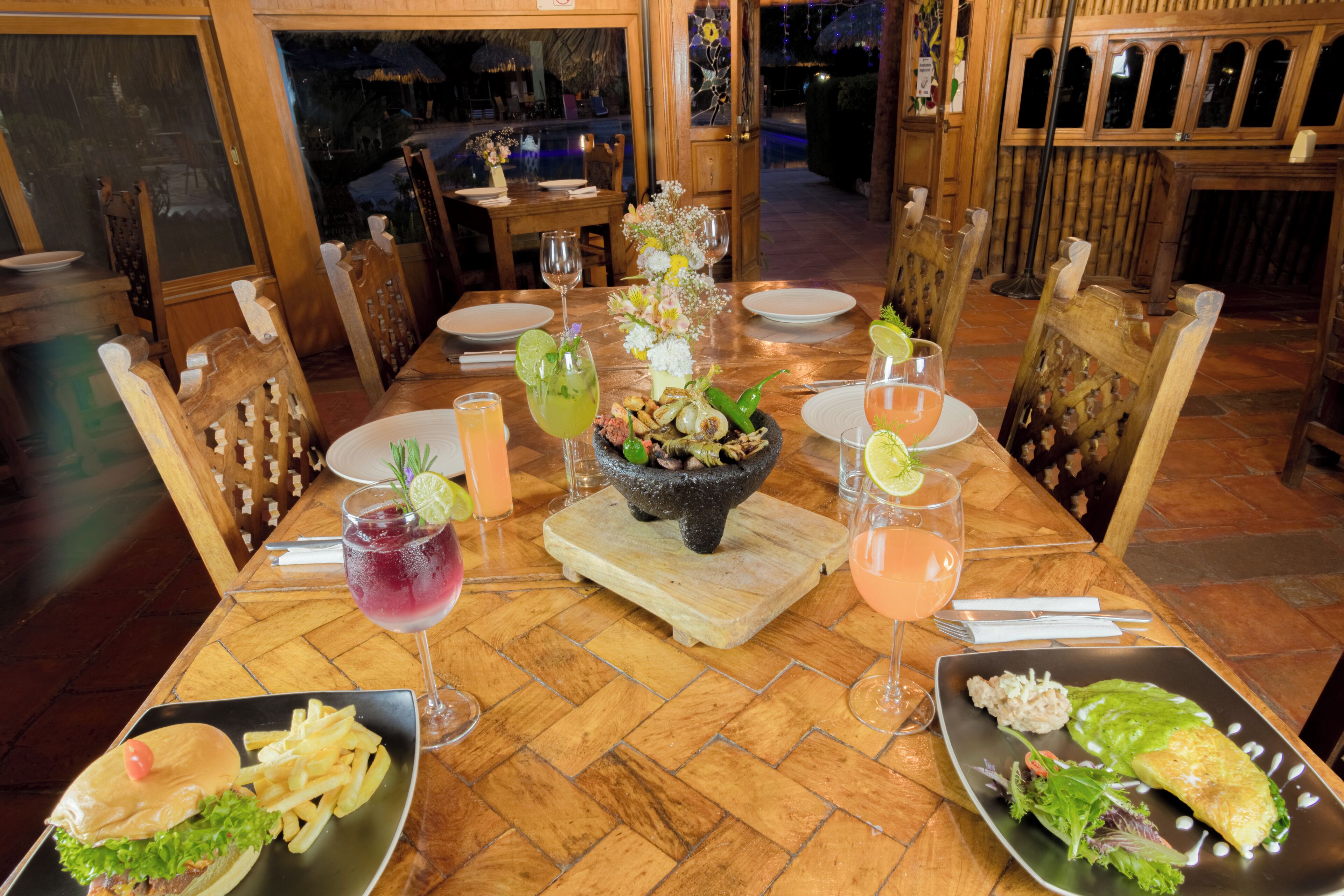 A dining table set with plates of food, drinks, and a centerpiece.