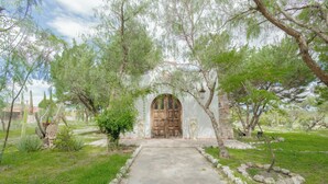 A stone pathway leading to a wooden door framed by a white wall with a decorative arch. - Hotel Atotonilco El Viejo (San Miguel de Allende)