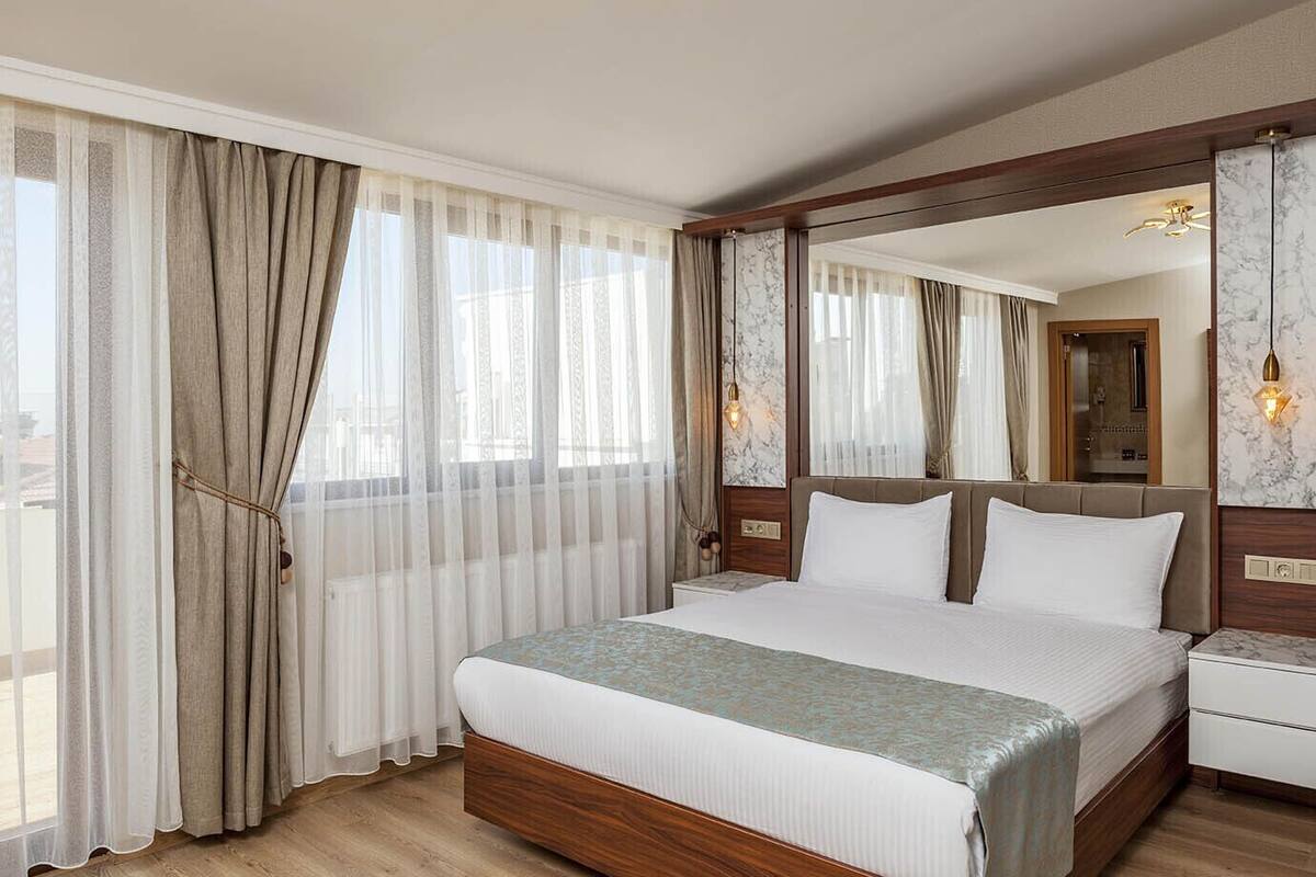 Une chambre d’hôtel avec un grand lit, une tête de lit en bois et un mur en marbre.