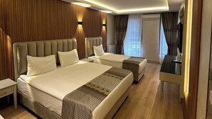 A modern bedroom with two beds, a bedside table, a TV, and a wooden accent wall. - Hotel Kupeli (Istanbul)