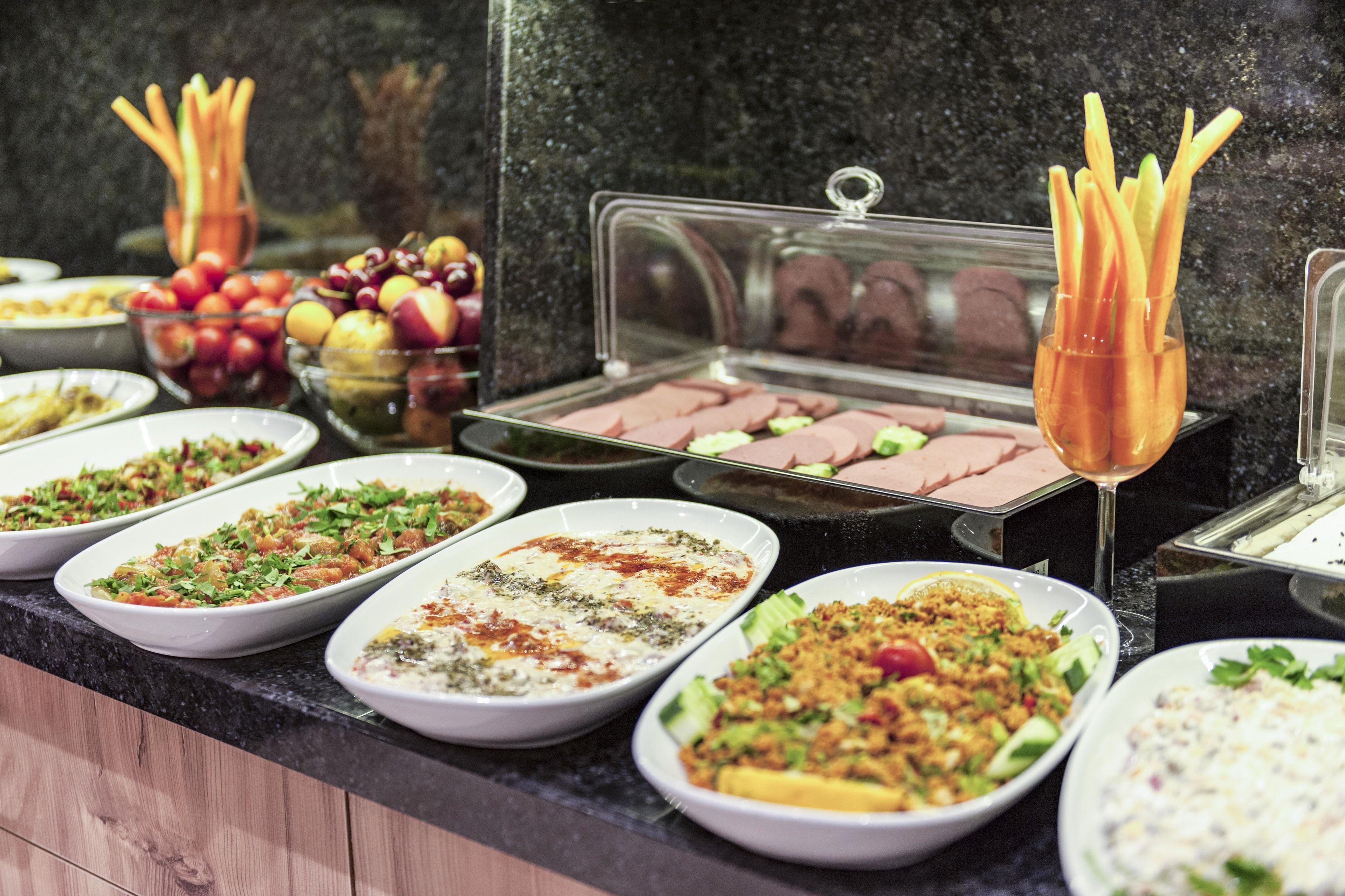 A buffet with various dishes including salads, meats, and fruits.