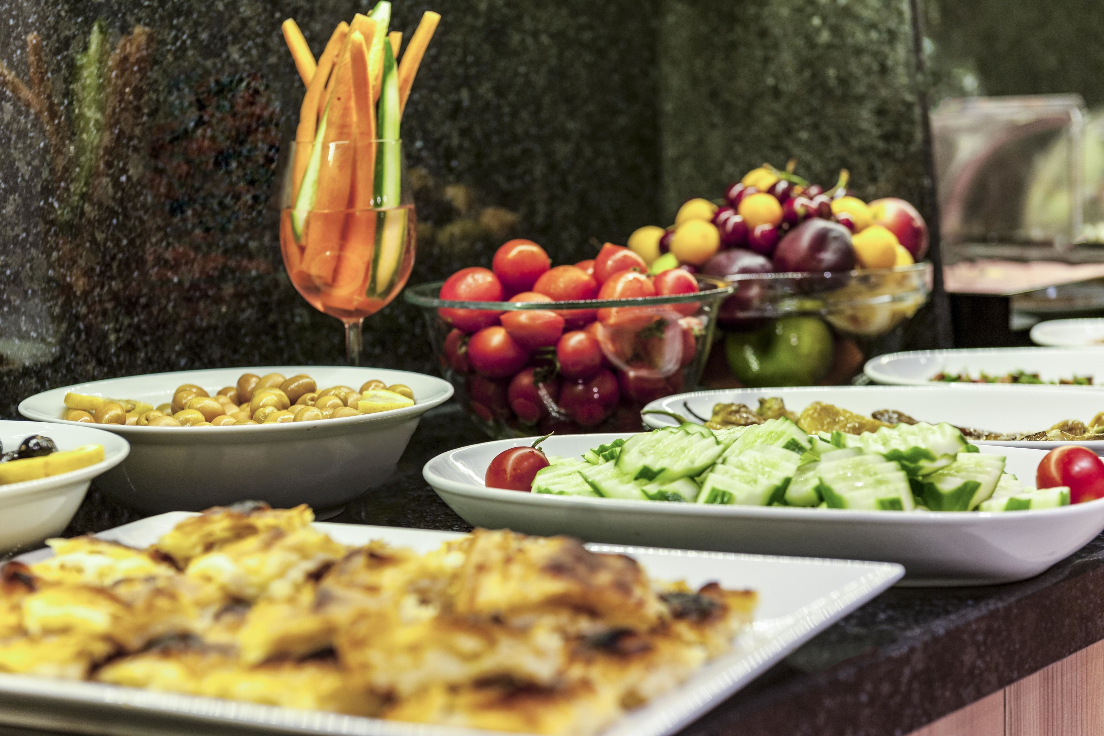 A buffet with various dishes including salads, fruits, and grilled items.