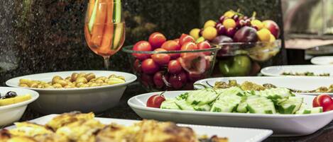 Buffet variado com diversos pratos, incluindo saladas, frutas e opções grelhadas.