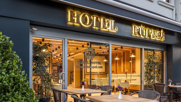 A hotel entrance with a modern design, featuring a glass facade and outdoor seating area. - Hotel Kupeli (Istanbul)