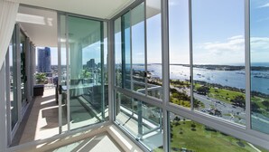 A high-rise apartment with large floor-to-ceiling windows offering a view of a marina and city skyline.