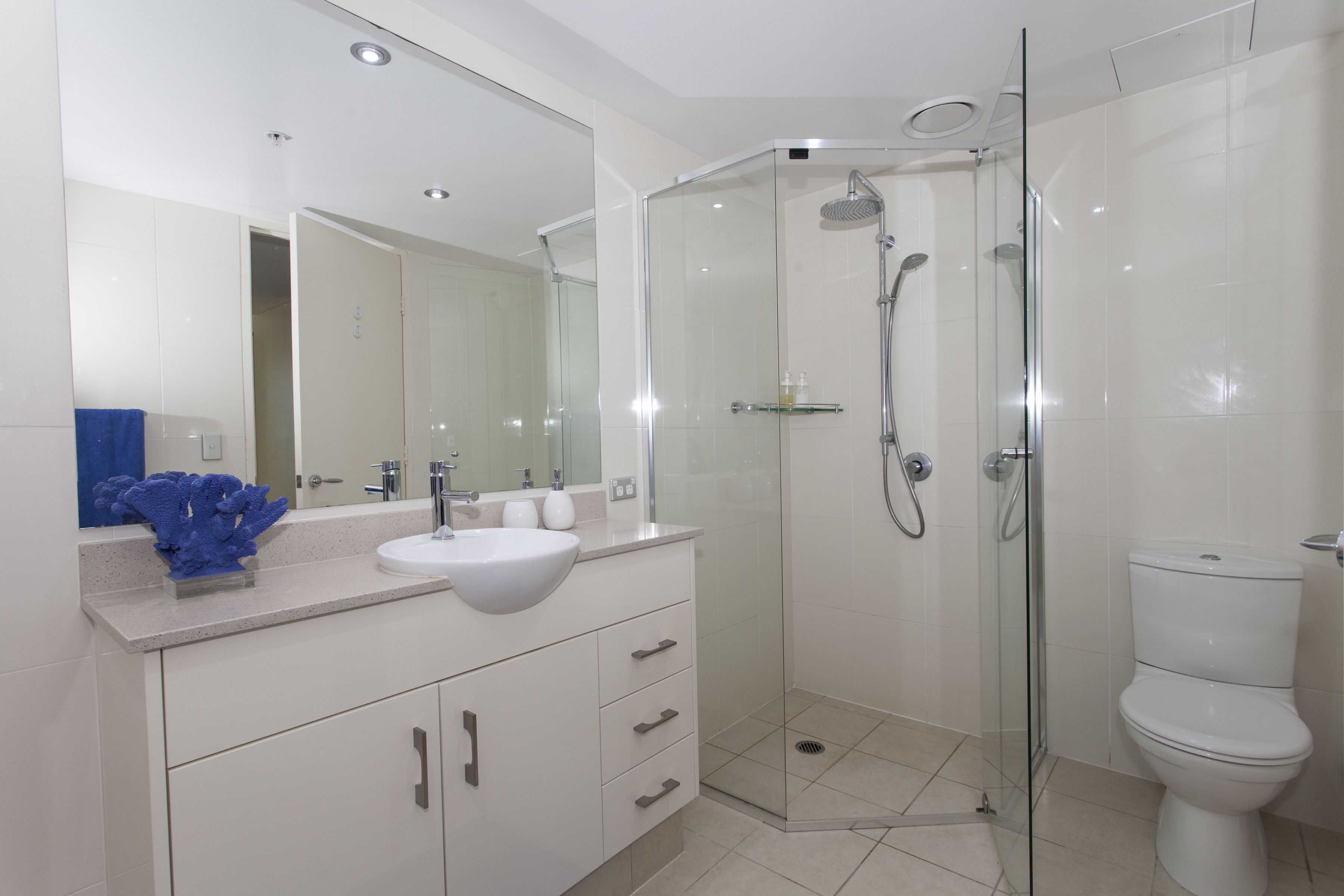 Een moderne badkamer met een douchecabine van glas, een wit wastafelmeubel en een toilet.