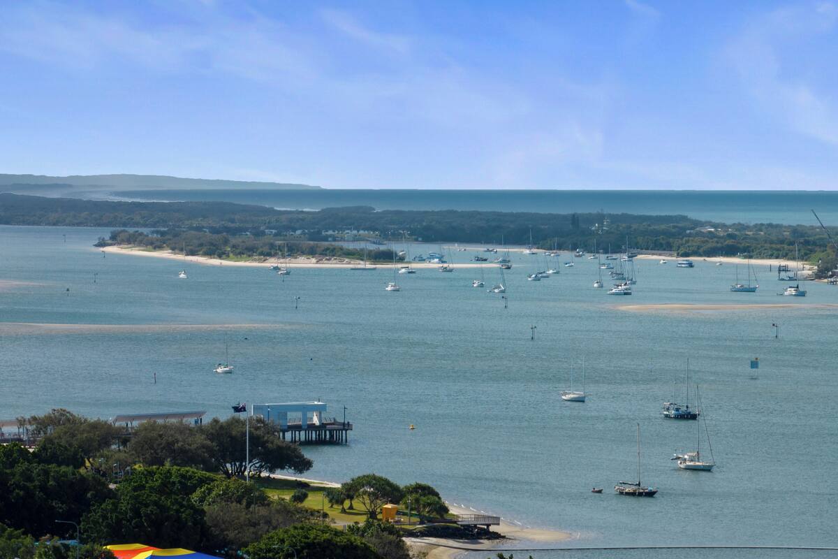 A coastal view with multiple boats, a pier, and a beach.