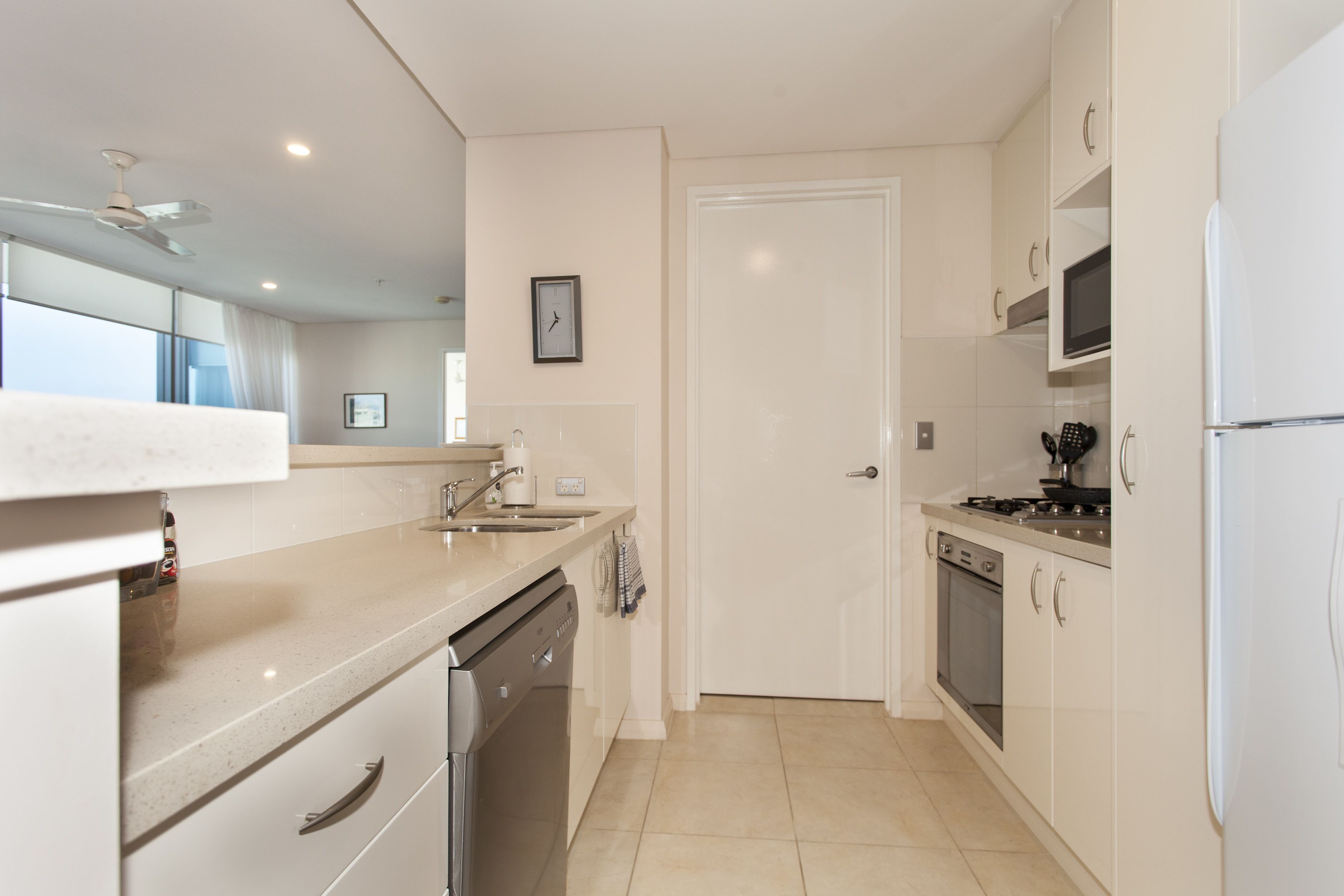 Una cocina moderna con armarios blancos, lavavajillas, estufa y refrigerador.