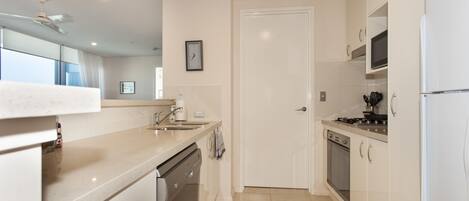 Una cocina moderna con armarios blancos, lavavajillas, estufa y refrigerador.