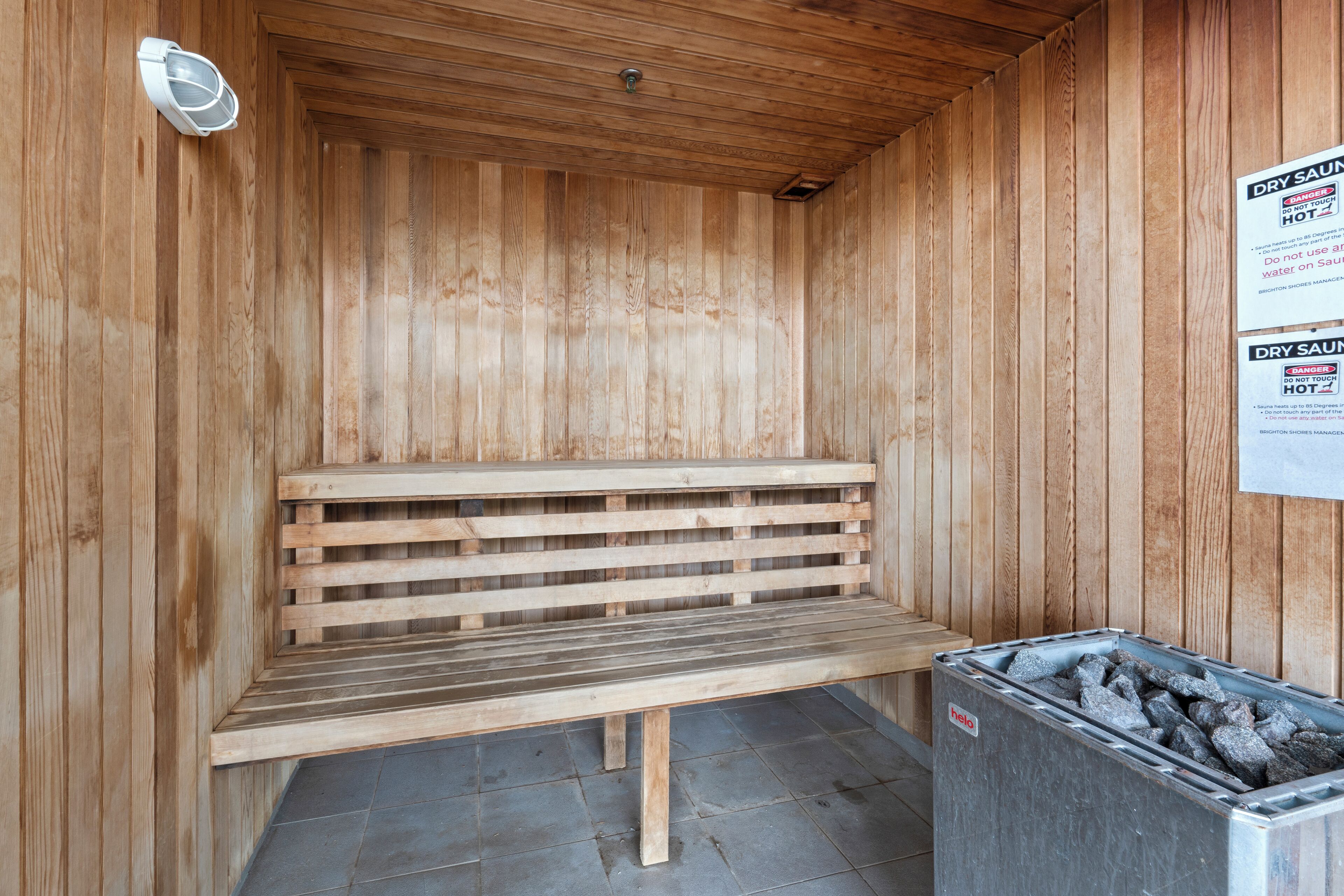 A wooden sauna with a bench and a charcoal bin.