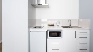 A modern kitchen with white cabinetry, a built-in microwave, a dishwasher, and a stainless steel range hood. - Mayfair Plaza Motel (Sandy Bay)
