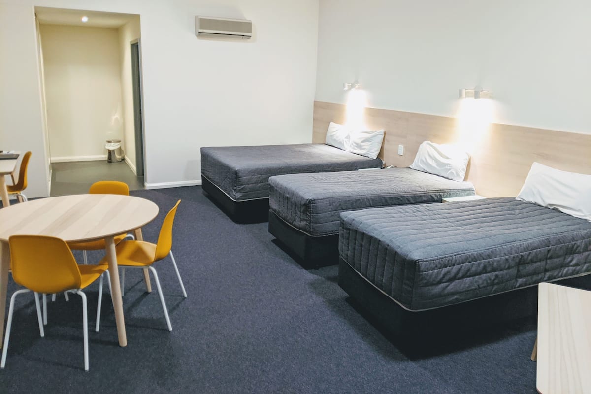 Hotellihuone, jossa on kaksi erillistä sänkyä, pieni pöytä ja kaksi tuolia.