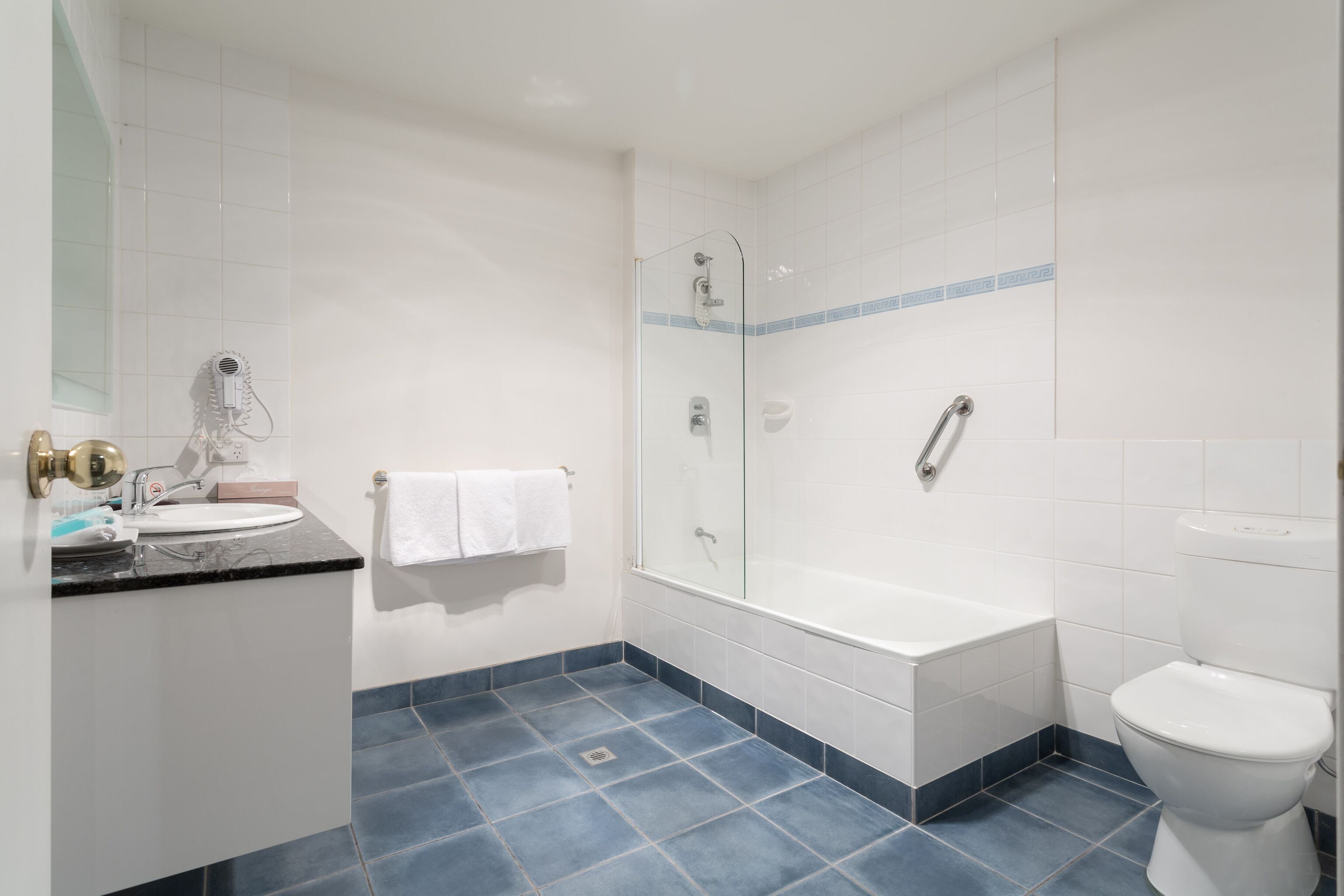 Ein Badezimmer mit Waschbecken, Spiegel, Handtuchhalter, Dusche, Badewanne und Toilette.